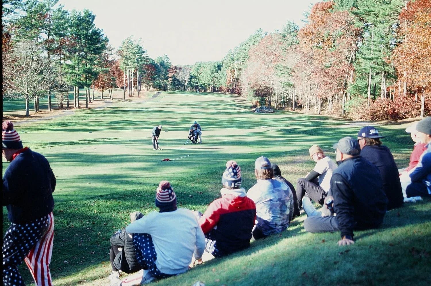 The whole field sitting on the hill above the fairway, watching a putt