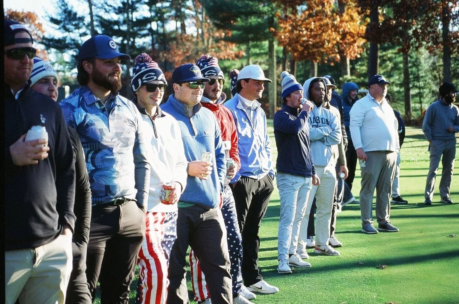 Players lined up along the tee box in beanies and USA pants