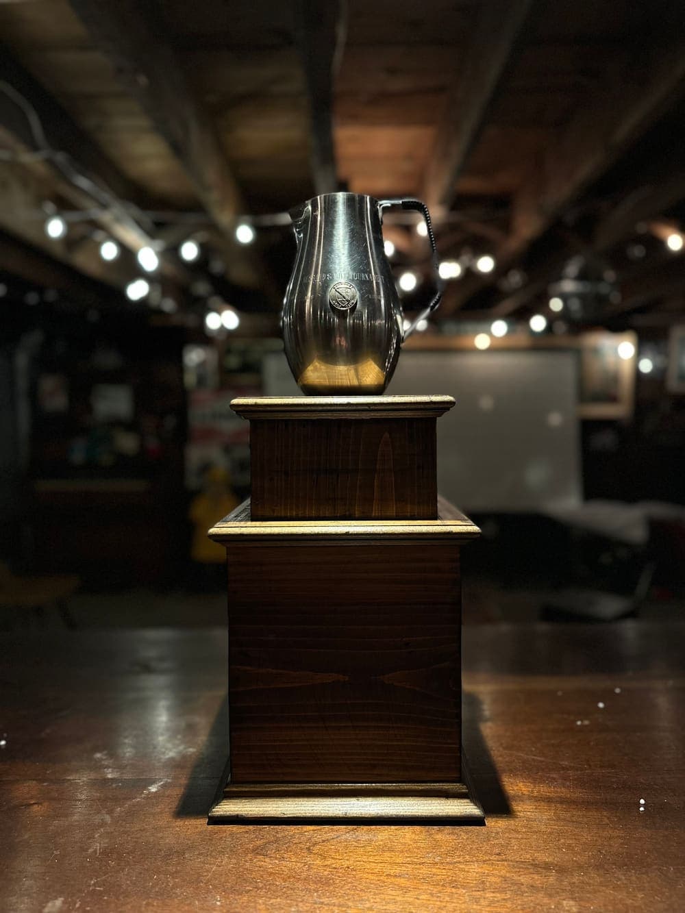 The Thanksgimme Classic trophy: the pewter pitcher on its wooden pedestal, under the basement lights